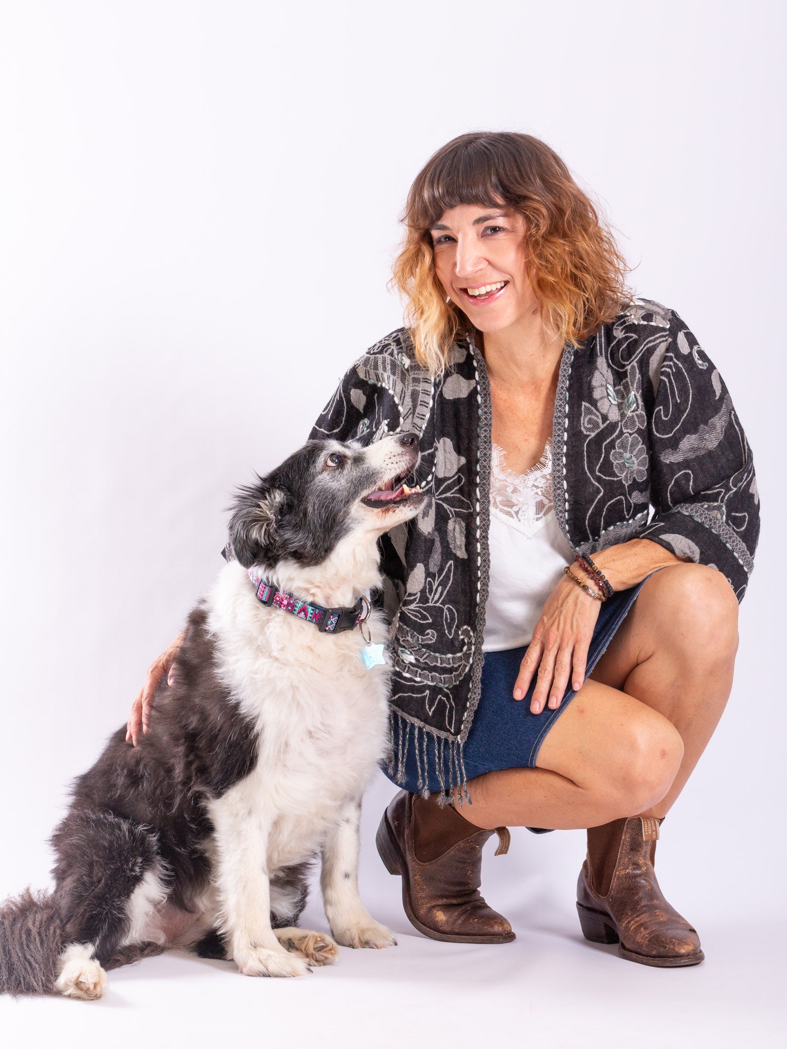 A wool fringed jacket in black and grey tones - on a model with dog
