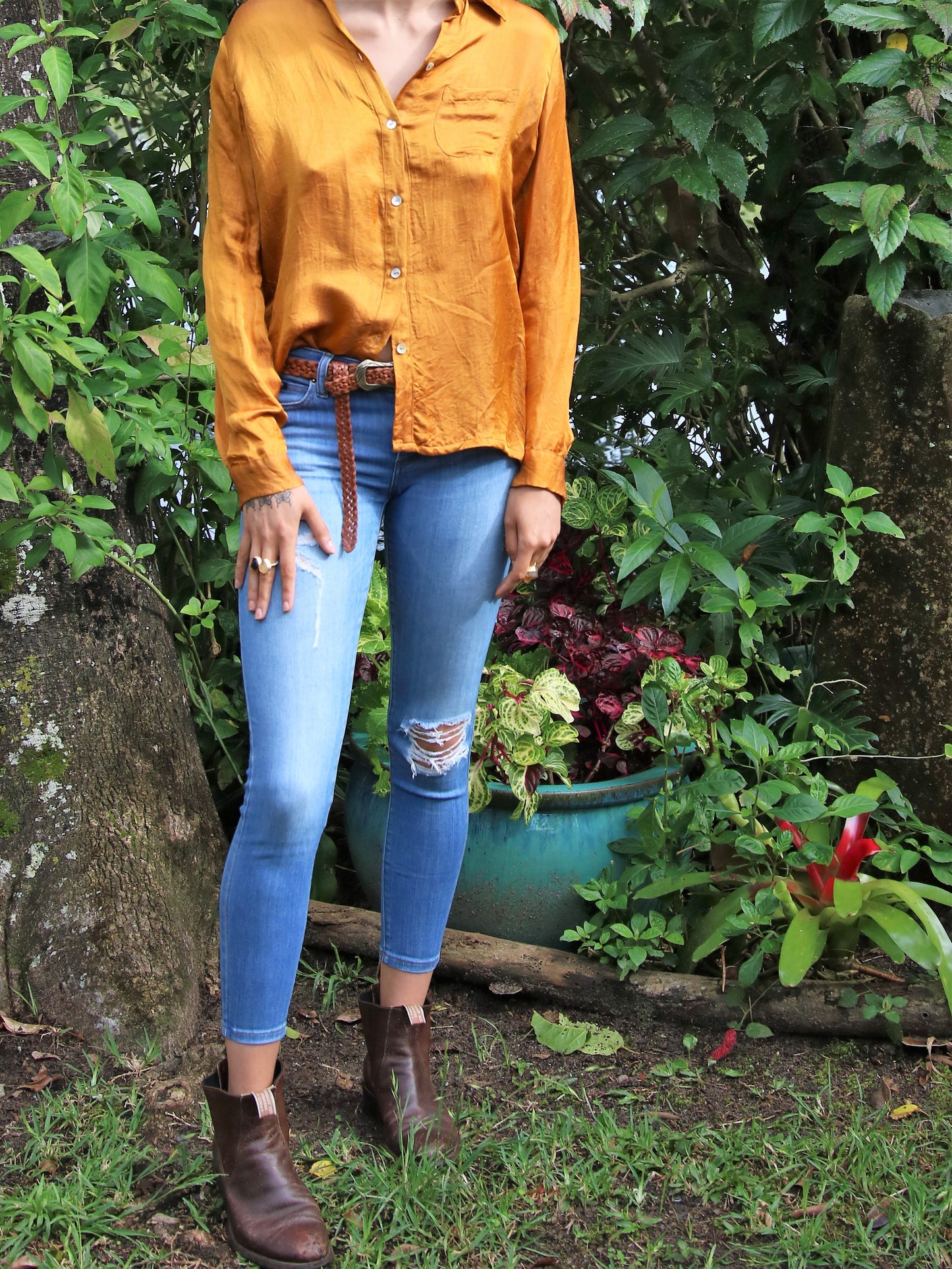 Woman wearing satin shirt, jeans and leather woven tfa belt