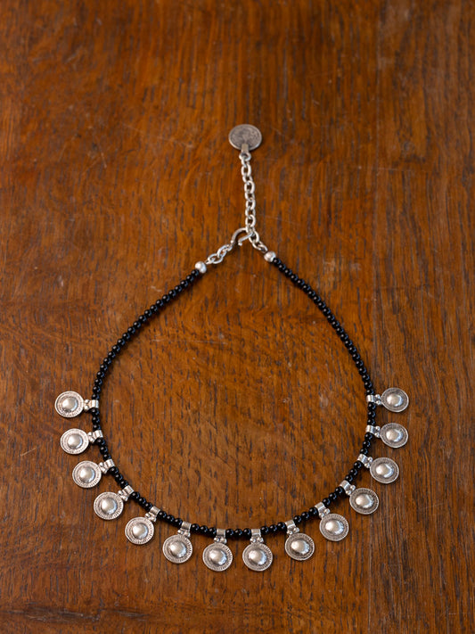 Necklace with black beads and silver discs threaded.